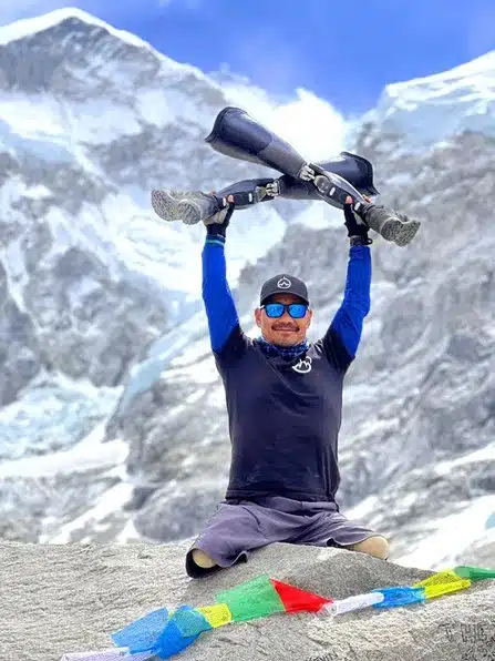Hari Budha Magar holding his prosthetic legs in the air