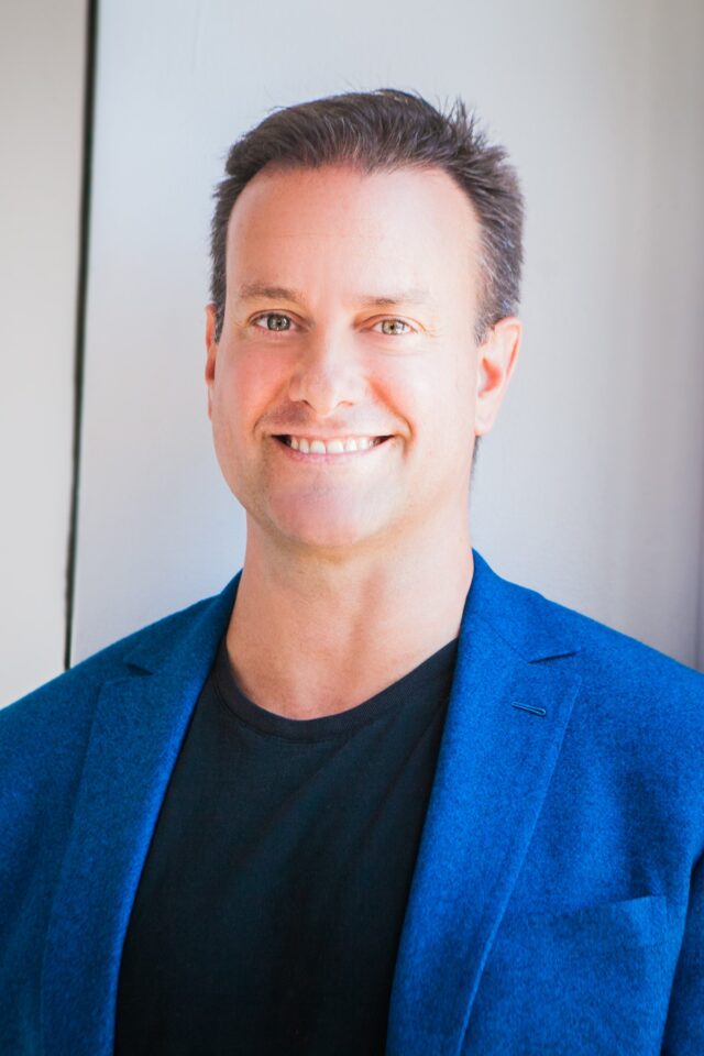 Greg Wells, leadership speaker in blue jacket